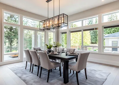 Dining area with large picture windows overlooking a forest, showcasing seamless indoor-outdoor design in trail bc.