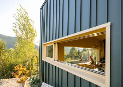 Exterior view of a unique horizontal "ribbon" window integrated into a modern wood-sided home in slocan bc.